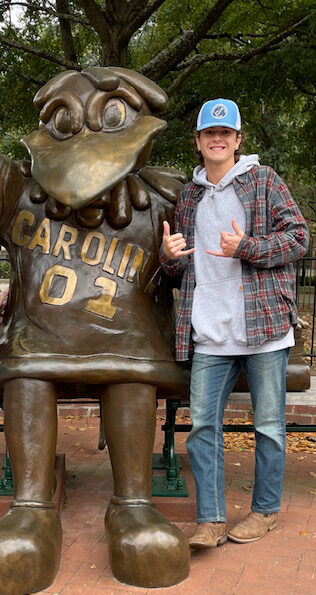 Photo of Nate with Cocky statue giving spurs up signs with his hands