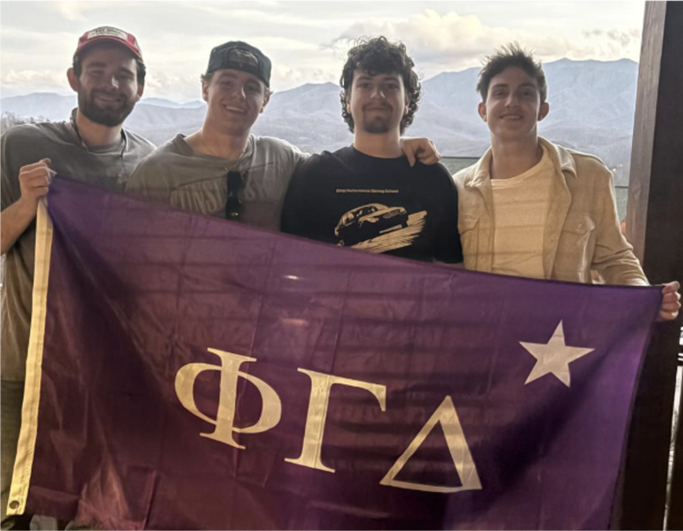 Photo of Nate with 3 fraternity brothers holding up Fiji flag